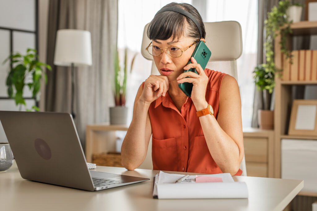 Featured image for an article. Image shows a woman sitting in front of a laptop and talking on the phone.